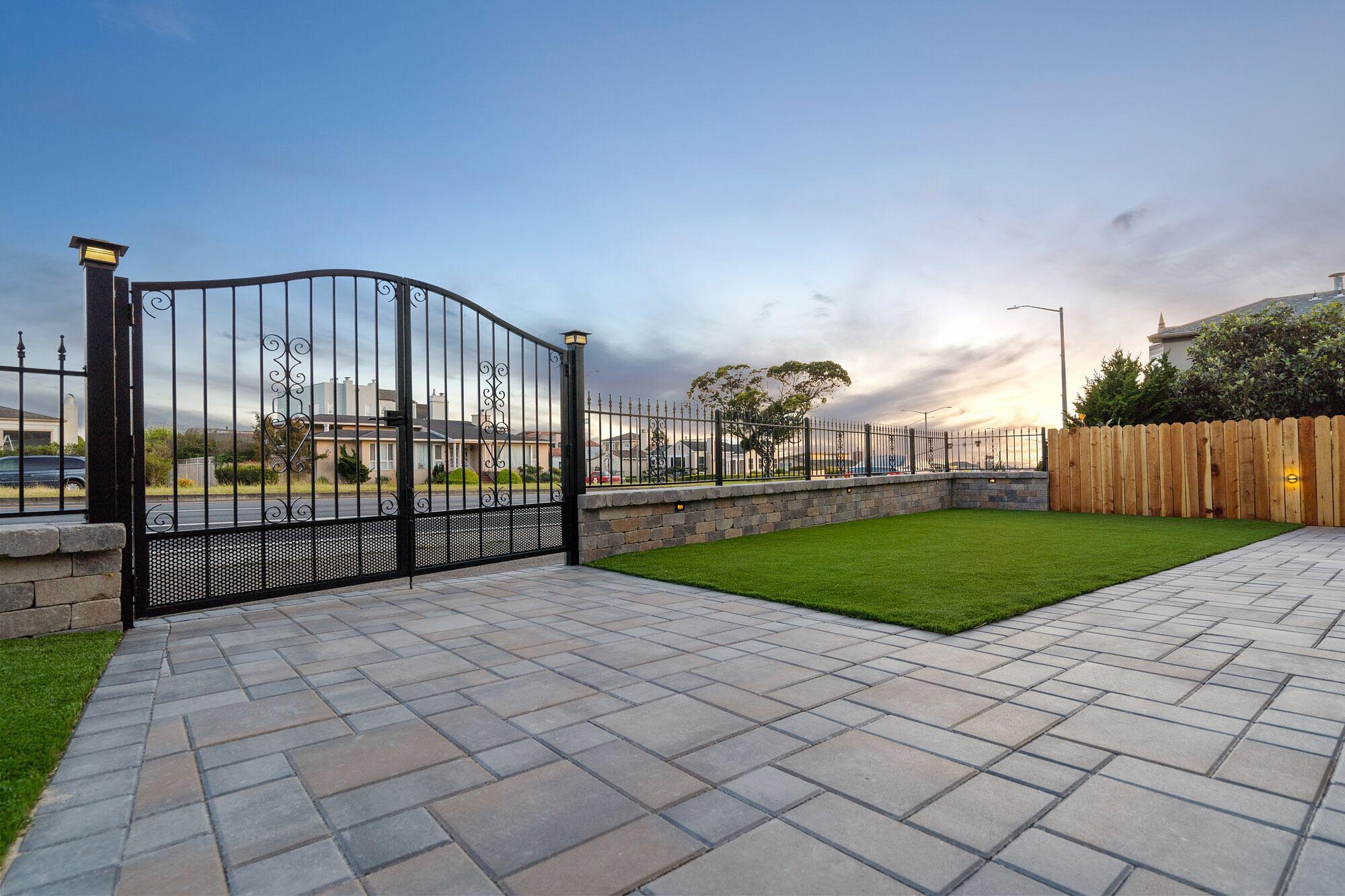 Stone paver patio with iron gates and fence.