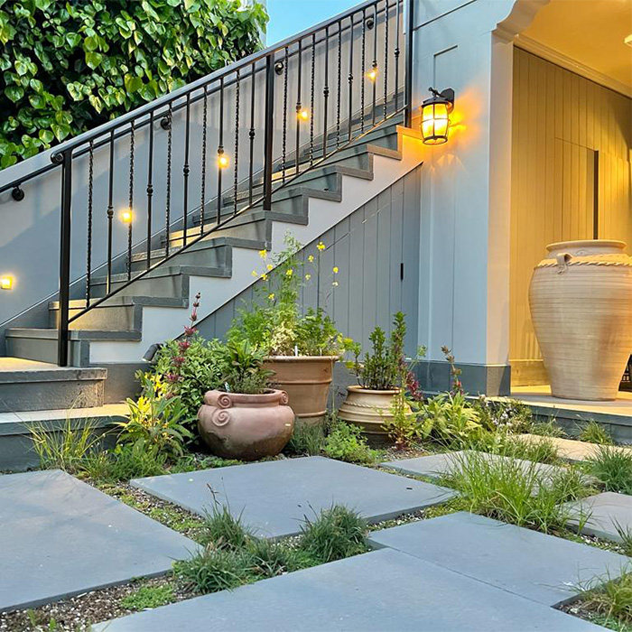 Patio renovation with square concrete slabs, iron stairway handles, and large Mediterranean style ceramic plant containers.